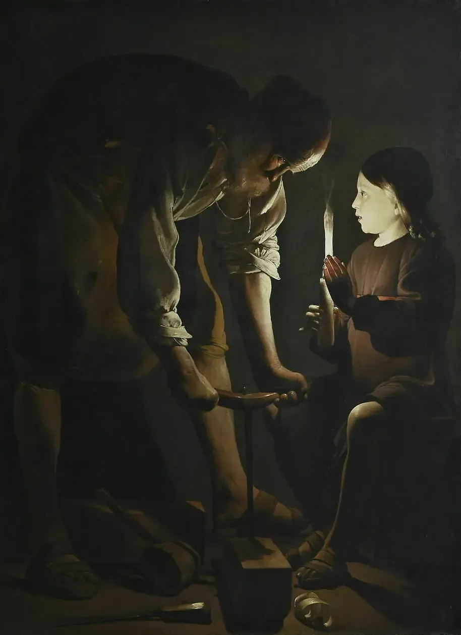 José trabaja la madera inclinado sobre una viga mientras el niño Jesús sostiene una vela que ilumina la escena.
